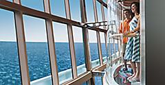 Couple in glass elevator over looking ocean waters from cruise ship