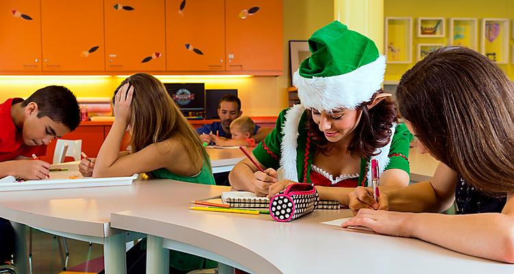 Oasis of the Seas, holiday, teens at tables in Adventure Ocean, father and son in background, family, young woman wearing green Santa''s elf outfit, hat and jacket, writing, coloring, drawing, fun