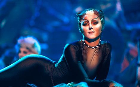 A woman dressed like a black cat with cat makeup during a Cats broadway show on Oasis.
