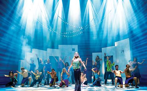 Woman standing on main stage with lights during a Mamma Mia broadway show onboard Allure