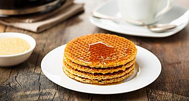 Stack of fresh Stroopwafels with honey and coffee, in a shop in Amsterdam, Netherlands