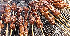 Indonesian street food, sate skewers on a grill. 