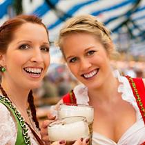 Young women in traditional Bavarian clothes - dirndl or tracht - on a festival or Oktoberfest in a beer tent