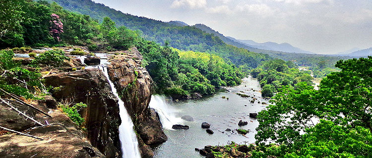 At the edge of the Athirapally Waterfall in Kerala, with a stunning view of the surrounding jungle and mountains in Cochin, India