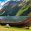 A replica viking boat with mountains in the background