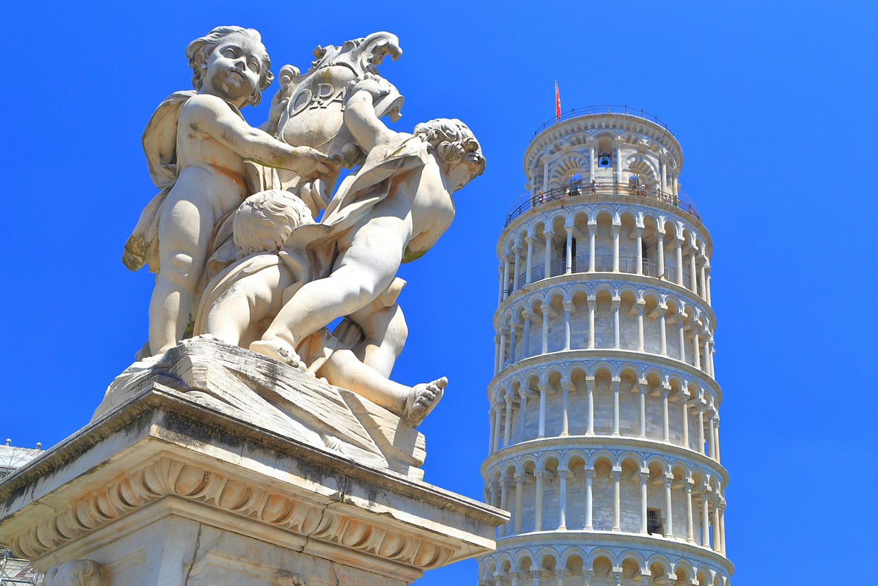 A marble statue with the Leaning Tower of Pisa in the background