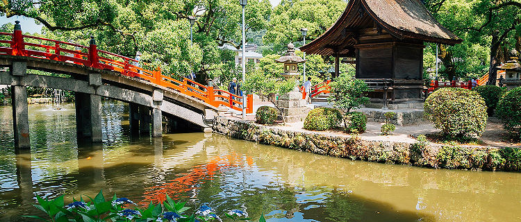 A red bridge over a water canal at the Dazaifu Tenmangu Shrine in Fukuoka, Japan
