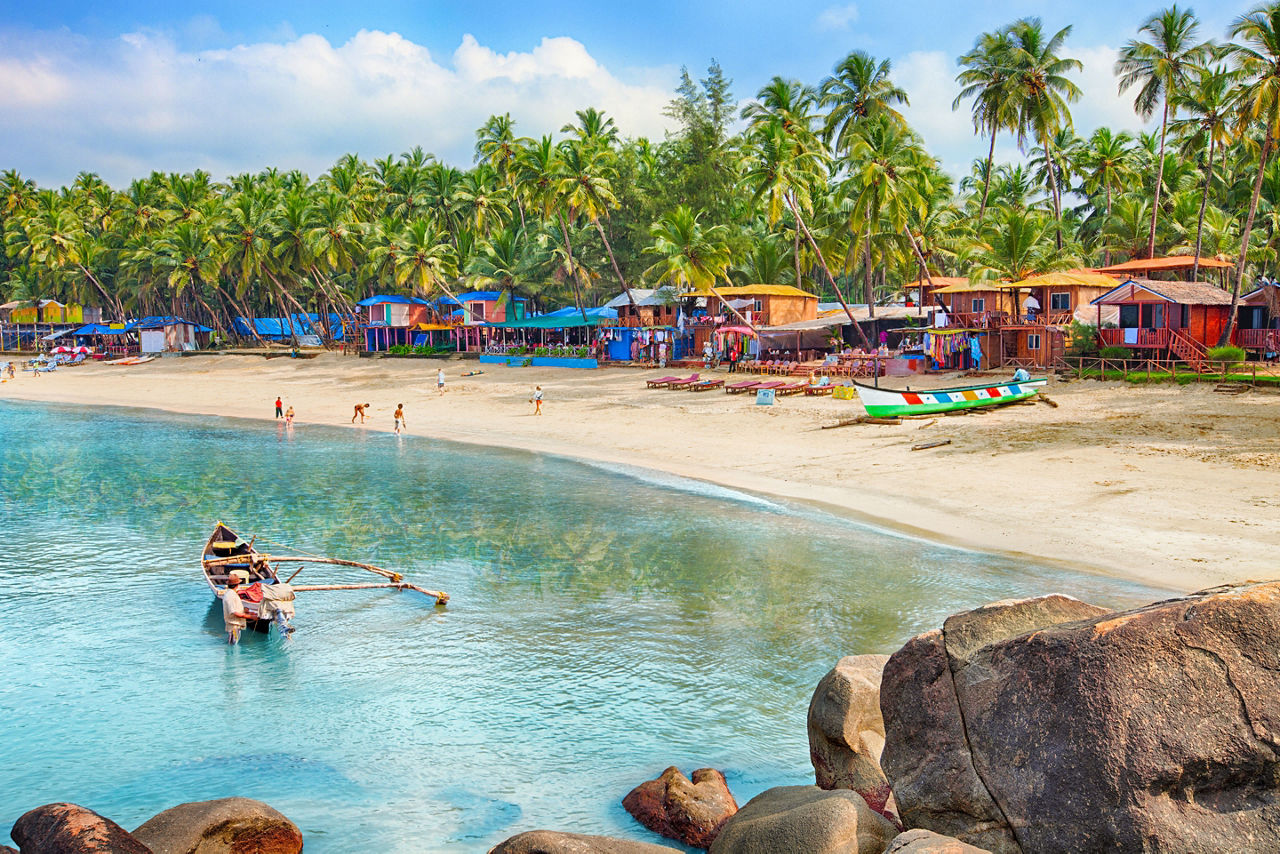The Palolem Beach with colorful beach huts and palm trees along the coast of Goa, India