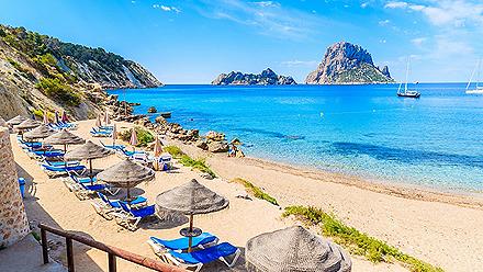Beach chairs lining Cala d'Hort Beach in Ibiza, Spain