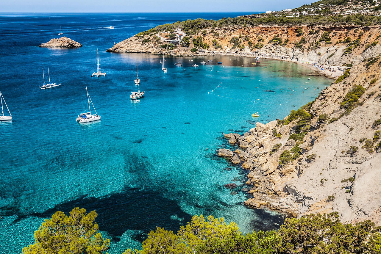 Boats anchored off a secluded beach in Es Verda Island, Ibiza, Spain