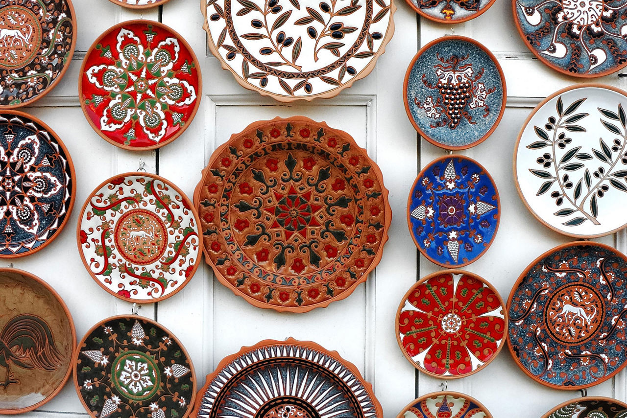 Assorted colorful plates with painted designs hanging on a wall