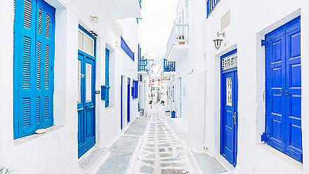 A street of white buildings with blue accents in Mykonos, Greece