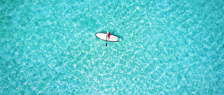 Woman on a stand up paddle boat over turquoise waters