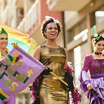 woman and her friends in carnival costumes and make-up on Mardi Gras parade.