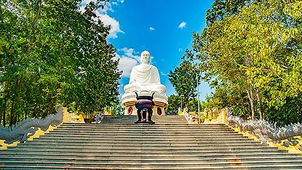 Giant white buddha statue at the top of a wide stair case in a temple in Nha Trang, Vietnam