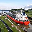 An industrial red ship entering the Panama Canal waterway that connects the Atlantic Ocean to the Pacific Ocean