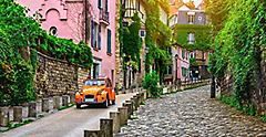 orange car driving along an old street in Paris. Europe.