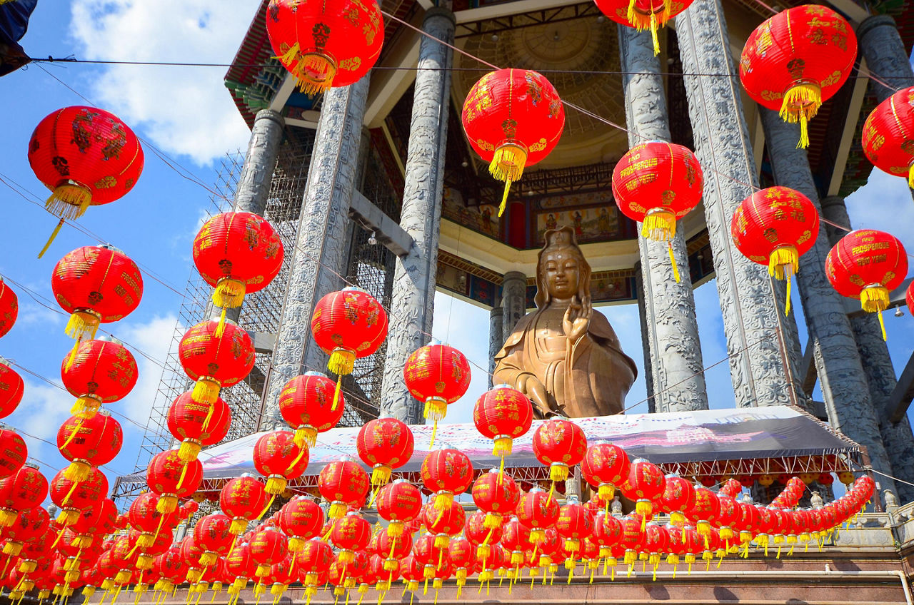 Red lanterns hanging from the buddha Guanyin statue in a Chinese temple in Penang, Malaysia