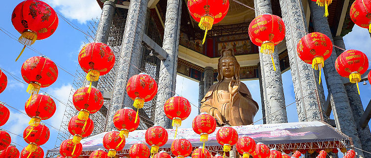 Red lanterns hanging from the buddha Guanyin statue in a Chinese temple in Penang, Malaysia