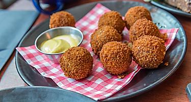 Eight bitterballen on a plate with a dipping sauce