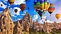 Colorful hot air balloon riders hovering over the rock formations of Cappadocia, Turkey.
