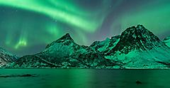 Amazing show of northern light ( aurora borealis ) above the mountains and fjords of Tromsø in the north of Norway