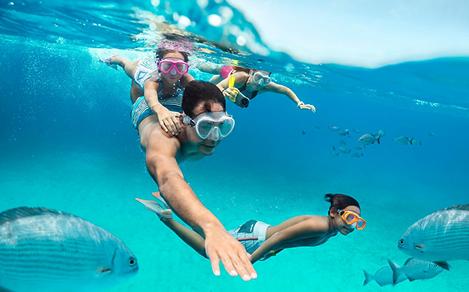 A family of four snorkeling with fish at CocoCay