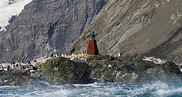 Penguins and bust of Captain Luis Pardo Villalon on the beach, Point Wild, Elephant Island, Antarctica.