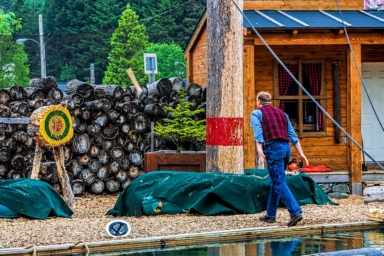 Lumber jack throwing axe at log target in tourist show