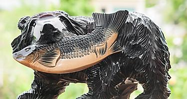 A tradiitonal Hokkaido wood carving of a bear with a salmon in its mouth