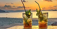 Glass of amber-gold Caribbean rum in front a sunset. The Caribbean.
