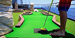 Man playing mini golf on a cruise ship open deck.